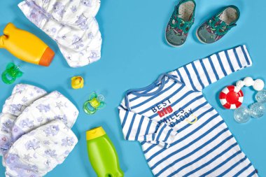 Baby care with bath set. Nipple, toy, clothes, shampoo on blue background top view mockup. Flat lay. Still life. Copy space