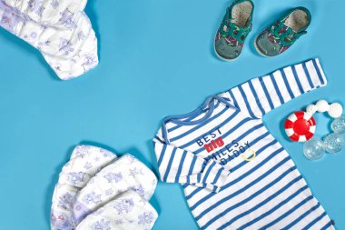 Baby clothing, toiletries, toys and health care accessories on blue background. Wish list or shopping overview for pregnancy.