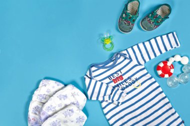 Baby clothing, toiletries, toys and health care accessories on blue background. Wish list or shopping overview for pregnancy.