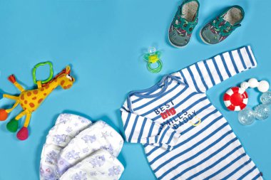 Baby clothing, toiletries, toys and health care accessories on blue background. Wish list or shopping overview for pregnancy.