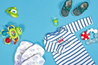 Baby clothing, toiletries, toys and health care accessories on blue background. Wish list or shopping overview for pregnancy.