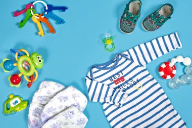 Baby clothing, toiletries, toys and health care accessories on blue background. Wish list or shopping overview for pregnancy.