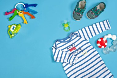 Baby clothing, toiletries, toys and health care accessories on blue background. Wish list or shopping overview for pregnancy.