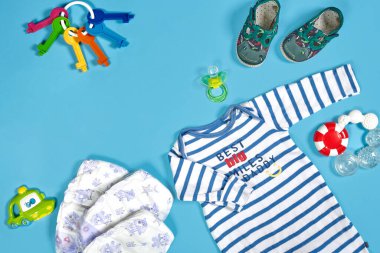 Baby clothing, toiletries, toys and health care accessories on blue background. Wish list or shopping overview for pregnancy.