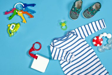 Baby clothing, toiletries, toys and health care accessories on blue background. Wish list or shopping overview for pregnancy.