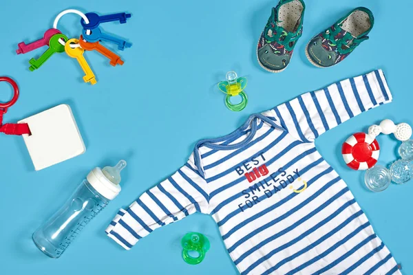 Baby clothing, toiletries, toys and health care accessories on blue background. Wish list or shopping overview for pregnancy.