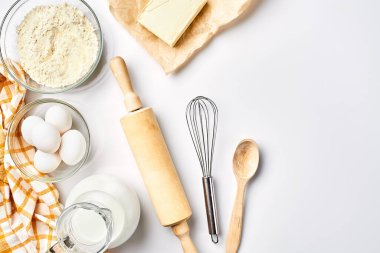 Hamur hazırlığı. Tarifteki malzemelerin miktarının ölçümü. Hamur için malzemeler: un, yumurta, merdane, çırpı, süt, tereyağı, krema. Üst görünüm, metin için boşluk. Devam et