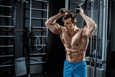 Seksi kaslı adam spor salonunda poz veriyor, karnı şekilli. Güçlü erkek, çıplak gövde kasları, vücut çalışıyor. Mavi şortlu sporcu