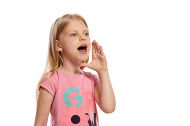 Close-up portrait of a beautiful blonde little girl with a long hair, in a pink t-shirt, calling someone while posing isolated on white background with copy space. Concept of a joyful childhood.