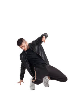 Full-length photo of a modern performer in glasses, black leather jacket, t-shirt, sports pants and light sneakers fooling around in studio. Indoor photo of a nice guy dancing isolated on white