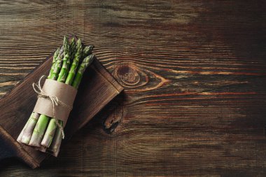 Bunch of an edible, juicy sprouts of asparagus on wooden background. Fresh, green vegetables, top view. Healthy food. Fall harvest, agricultural farming concept.