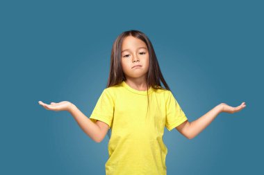 Surprised child girl with spread arms on blue background