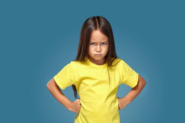 Angry little kid showing frustration and disagreement on blue background