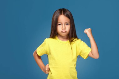 Angry little kid showing frustration and disagreement on blue background
