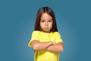 Angry little kid showing frustration and disagreement on blue background