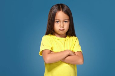 Angry little kid showing frustration and disagreement on blue background