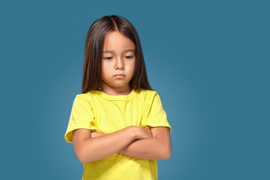 Angry little kid showing frustration and disagreement on blue background