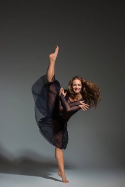 Young beautiful dancer in black dress posing on a dark gray studio background. Modern, Contemporary, improvisation