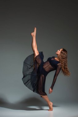 Young beautiful dancer in black dress posing on a dark gray studio background. Modern, Contemporary, improvisation