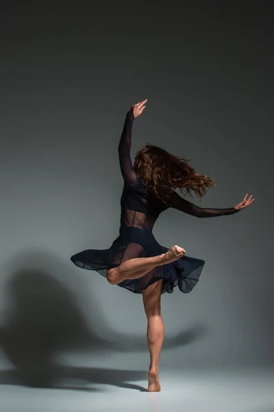 Young beautiful dancer in black dress posing on a dark gray studio background. Modern, Contemporary, improvisation