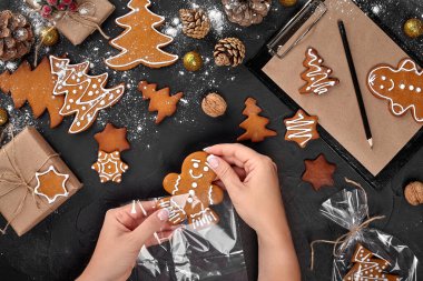 Noel hediye gingerbread koyu arka plan üzerinde. Noel Gingerbread çerezleri. Bisküvi şenlikli ambalajında. Kadın krema şeker ile Noel gingerbread çerezleri ambalaj. Tatil, kutlama ve