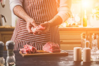 Yemek hazırlanması. Yemek, et Dana bonfile işleme. Kişi mans el et - tuz, karabiber ile sprinkles dinlendirir. Siyah ahşap masa, baharatlar ve otlar çerçeve içinde.