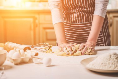 Mutfak masasında yoğurma hamur eller kadın. Çizgili bir önlük bir kadın mutfakta yemek