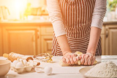 Mutfak masasında yoğurma hamur eller kadın. Çizgili bir önlük bir kadın mutfakta yemek