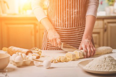 İki kadının el görünümünü yakın çekim bıçak hamur kesme. Çizgili bir önlük bir kadın mutfakta yemek