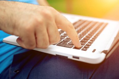 Yakın çekim yakışıklı kadeh dizüstü bilgisayar ekran dokunmadan eller mans. Dizüstü bilgisayar kullanan ve yerde oturan işadamı... Güneş parlaması