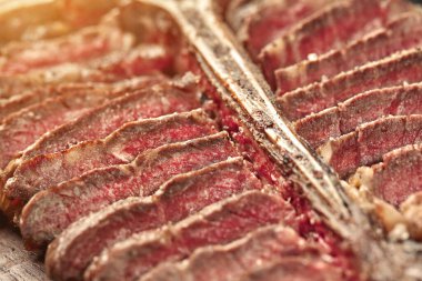 Sliced Steak T-bone lying on wooden board. Close-up. Top view. Still life. Sun flare