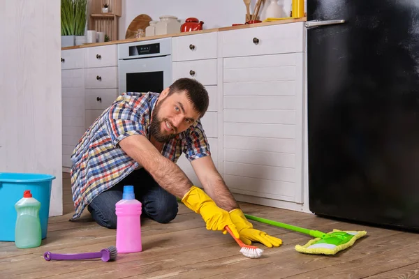 집안청소 셔츠에 남자는 부엌의 바닥에 수건과 브러시를 사용하여 청소하려고 — 스톡 사진