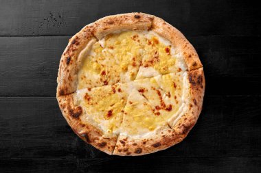Eritilmiş mozzarella ile kaplanmış kahverengi kenarlı, ince klasik hamurlu, iştah açıcı peynirli pizza, siyah ahşap arka planda parmesan peyniri, üst manzara. Popüler İtalyan mutfağı kavramı