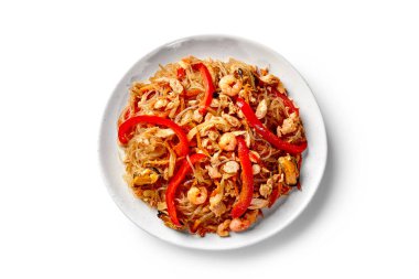 Baharatlı pirinç eriştesi, kızarmış karides, midye, kalamar ve sebzeler tabakta servis ediliyor. Üst manzara beyaz arka planda izole. Geleneksel Çin mutfağı