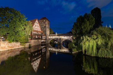 Ortaçağ kulesi ve nehir boyunca yarı ahşap evle Nuremberg 'de yansımaları olan eski güzel bir köprü.