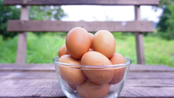 杯子里的新鲜鸡蛋放在花园中央的一张木制桌子上 — 图库照片