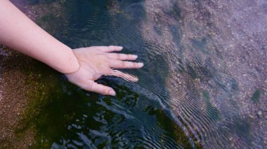 Temiz suyu tutan el, bahçenin yanındaki dereden alınan doğal kum tanelerini gören..