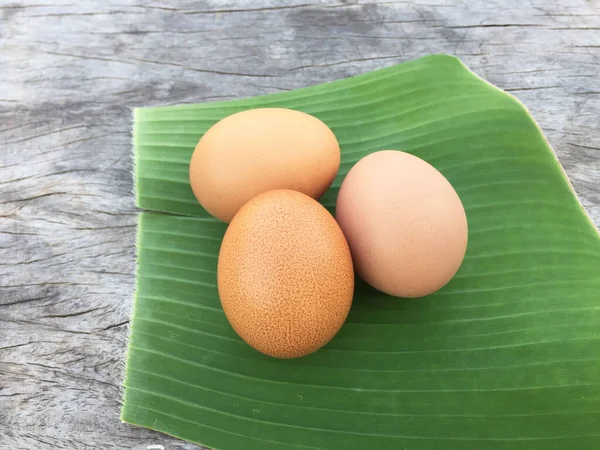 Three eggs on a banana leaf Placed on a wooden floor, healthy food is high in vitamins.