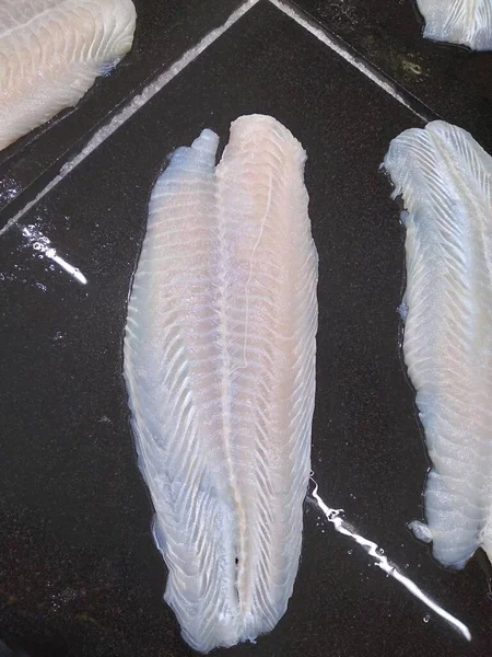 Phantasies Fish Fillet fresh berry on black surface high protein food beneficial to the body.