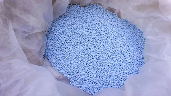 Bahçede yetişen bitkileri beslemek için plastik torbalarda bulunan granüler kimyasal gübre..