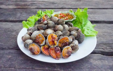Tahta bir masadaki beyaz tabakta salatalı taze midyeler ve deniz ürünleri soslu yüksek proteinli deniz ürünleri sağlıklı bir yaşam için kanı besler. (2)
