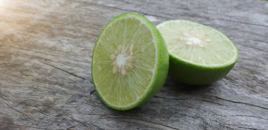 Yarım dilimlenmiş limonlar eski ahşap bir zemine serilmiş güneş ışığı vitaminlerle dolu sağlıklı meyvelerin arasından parlıyor..