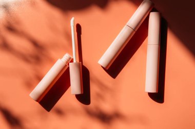 Dudak parlatıcısı için pembe temiz makyaj fırçası, açık bir tüpün yanında sıvı ruj, kapalı kozmetik tüpleri, maskara, gölgeli pembe göz kalemi. Boşluğu kopyala