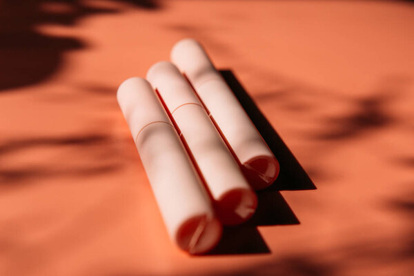 розовый закрытые трубки туши, подводка для глаз, блеск для губ, жидкая помада на фоне персика с тенями, скопировать пространство