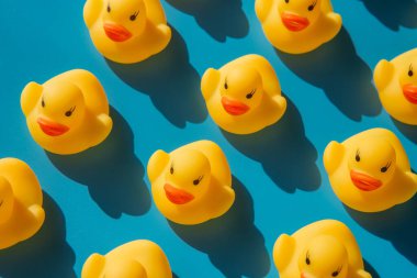 Katı gölgeli mavi arka planda sarı plastik ördekler