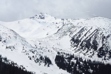 beautiful view of the mountains.  The valley is visible.  Small trees are somewhere below.  White snow lies on the mountains.