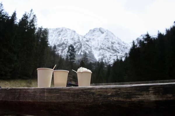 3 cups of coffee.  Beautiful large mountains are visible in the background.  Green forest around.  Beautiful nature
