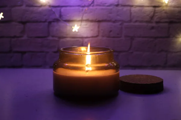 Una vela encendida en el fondo de una pared de ladrillo. Luz púrpura. —  Fotos de Stock