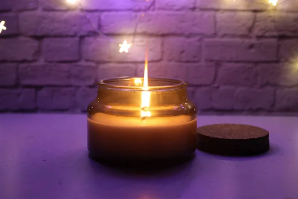Una candela accesa sullo sfondo di un muro di mattoni. Luce viola. — Foto Stock
