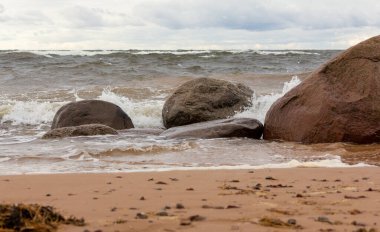 Sert sonbahar rüzgarında deniz kıyısında. Dalgalar kayalara çarpıyor.